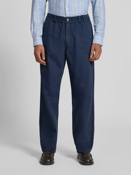 Mężczyzna nosi Jeans mit elastischem Bund od Forét, granatowa bawełna, krój straight fit, kieszenie z tyłu, zapięcie na guzik i zamek, szerokość w rozmiarze M: 80 cm, długość wewnętrzna nogawki: 38 cm, widok z przodu, całej sylwetki.