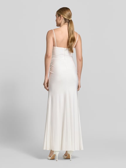 Frauenmodel trägt Abendkleid mit seitlichem Gehschlitz und Spaghettiträgern von Hey Kyla, Baumwoll-Mix mit Stretch-Anteil, Maxikleid, körpernaher Schnitt, V-Ausschnitt, Raffungen, rückseitiger Haken- und Reißverschluss, glatter Stoff in Weiß, Ganzkörperansicht Rückansicht.
