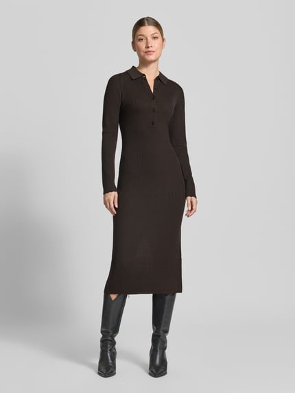 Frauenmodel trägt figurbetontes, braunes Strickkleid mit Polokragen und Knopfleiste Modell 'AMARILA' von DRYKORN, Ripp-Optik, Midikleid, Ganzkörperansicht von vorn.