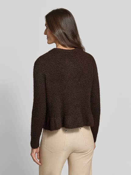 Frauenmodel trägt Regular Fit Strickjacke mit Woll-Anteil Modell 'Bows' von VILA in Dunkelbraun, beige Hose, gerippte Abschlüsse, Ganzkörperansicht Rückansicht.