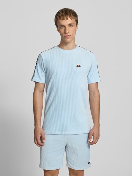 Männermodel trägt Herren T-Shirt mit Logo Modell 'MADORI' von Ellesse in Hellblau, Baumwoll-Mix mit Stretch-Anteil, Regular-Fit, Rundhalsausschnitt, Ganzkörperansicht von vorne.