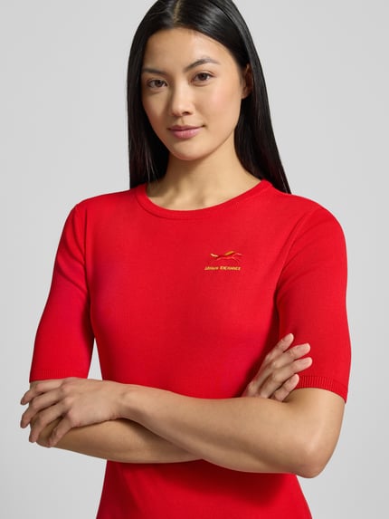 Kobiece modelka nosi knielanges Kleid aus Viskose-Mix mit Label-Stitching od ARMANI EXCHANGE w kolorze czerwonym, zbliżenie na górę ciała. Context: sukienka damska, figurę podkreślający krój, długość do kolan, okrągły dekolt, długość tyłu w rozm. S: 91 cm, szerokość biustu: 39 cm, długość rękawa: 28 cm.