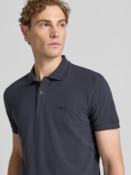 Męski model ma na sobie koszulkę polo Regular Fit Poloshirt aus reiner Baumwolle model 'PIO 1' od BOSS Green w kolorze ciemnoszarym, gładka faktura, zbliżenie górnej części ciała.