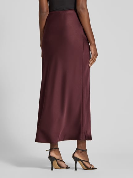 Frauenmodel trägt Maxirock aus Satin Modell 'Vicky' von Neo Noir in Bordeaux, glatte Textur, elastischer Bund, Ganzkörperansicht Rückansicht.