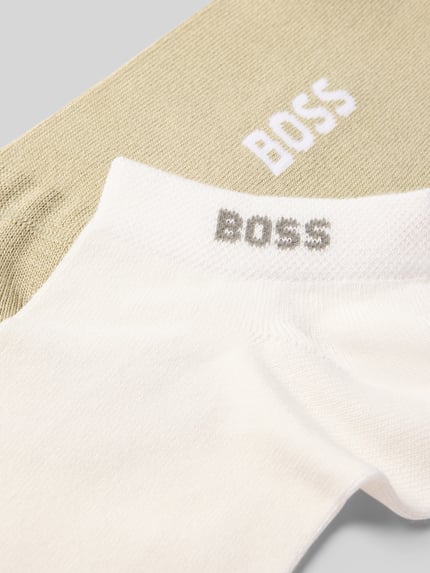 Produktfoto, zwei Paar Füsslinge aus Viskose-Mix Modell 'CHRIS' von BOSS in Beige und Weiß, weiche Textur, glatte Oberfläche. Herren Füsslinge von BOSS