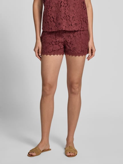 Frauenmodel trägt Regular Fit Sweatshorts mit Spitze Modell 'HONEY' von Vero Moda, einfarbig in Bordeaux, Baumwoll-Mix mit Spitzenmuster, Nahaufnahme Oberschenkel.
