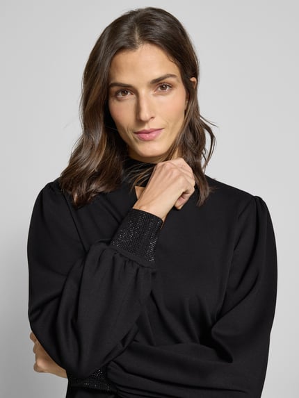 Vrouwenmodel draagt Sweatshirt met Stehkragen und Cut Out van monari, zwart, regular fit, viscosemix, pofmouwen, detailopname bovenlichaam.