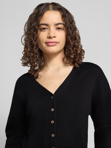 Frauenmodel trägt Regular Fit Cardigan mit Viskose-Anteil Modell 'Compact' von Topshop in Schwarz, Strick-Optik, V-Ausschnitt, Nahaufnahme Oberkörper. Baumwoll-Mix mit Viskose-Anteil, Rückenlänge bei Größe S 50 cm, Ärmellänge 55 cm.