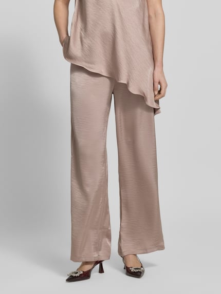 Frauenmodel trägt Hose aus Satin mit elastischem Bund von Little Mistress in Beige, Wide-Leg, Satin-Haptik, Bundweite 34 cm, Innenbeinlänge 76 cm, Nahaufnahme Unterkörper, Vorderansicht.