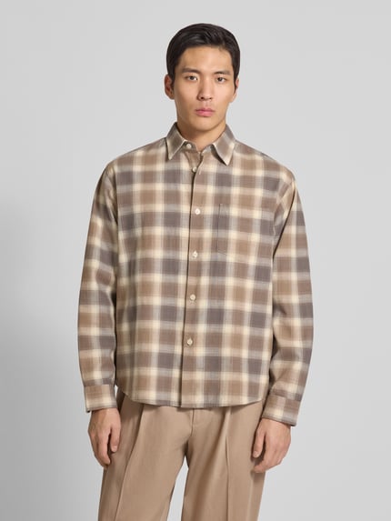 Männermodel trägt Regular Fit Freizeithemd aus reiner Baumwolle Modell 'CTMENZO' von SELECTED HOMME in Beige mit Gitterkaro, Kentkragen, einreihiger Knopfleiste, Brusttasche, Rückenpasse, Langarm mit Sportmanschette, Optik: Unifarben, Materialverarbeitung: Twill, Ganzkörperansicht von vorne.