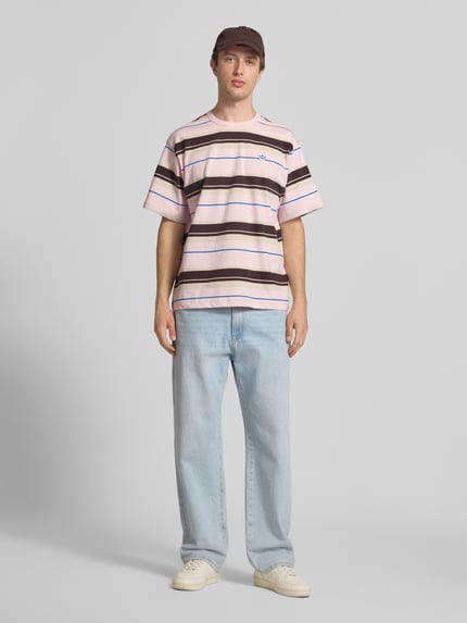 Männermodel trägt Regular Fit T-Shirt aus reiner Baumwolle von adidas Originals, mehrfarbig, gestreift, Logo-Stitching, Ganzkörperansicht von vorne.