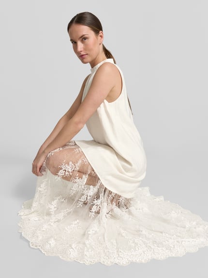Frauenmodel trägt Relaxed-Fit Maxikleid aus Viskose-Mix Modell 'Tenley' von Copenhagen Muse mit Semitransparenz, Spitzenbesatz, Ärmelloses-Design, Stehkragen, cremefarben, detailreiche Textur, Nahaufnahme Oberkörper.