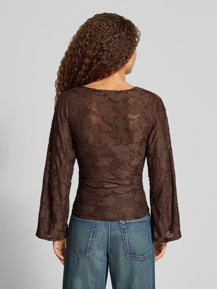 Frauenmodel trägt Langarmshirt mit Mesh Ausbrenner-Effekt von ONLY in Braun mit Spitze, langen ausgestellten Ärmeln, Rückansicht.