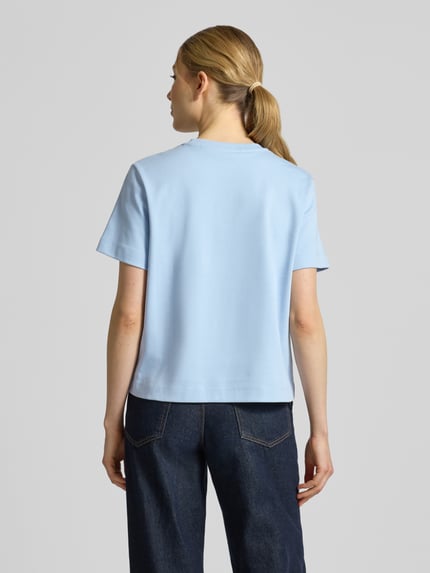 Frauenmodel trägt Regular Fit T-Shirt aus reiner Baumwolle Modell 'SARA' von Vero Moda in Optik: Unifarben, Materialverarbeitung: Jersey, Logo-Stitching, Rundhals, Kurzarm, Ganzkörperansicht Rückansicht