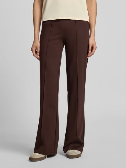 Frauenmodel trägt Straight Fit Stoffhose mit Viskose-Anteil von Smith and Soul, dunkelbraun, elastischer Bund, Bundfalten, seitliche Eingrifftaschen, Material-Mix, Ganzkörperansicht von vorne.