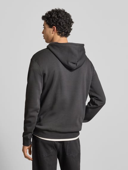 Männermodel trägt Regular Fit Hoodie aus Baumwoll-Mix Modell 'CERES' von Only & Sons, uni, label stitching, kangoeroezak, capuchon, sweat, zwart, ganzkörperansicht rückansicht.