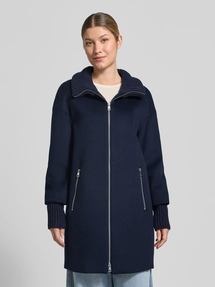 Frauenmodel trägt Mantel aus Woll-Mix mit Reißverschlusstaschen von White Label in Dunkelblau, Regular Fit, Stehkragen, Reißverschluss, zwei seitliche Reißverschlusstaschen, strukturierte Ärmelbündchen, glatte Oberfläche, Ganzkörperansicht von vorne. Rückenlänge 86 cm, Schulterbreite 55 cm, Brustweite 55 cm, Ärmellänge 56 cm.