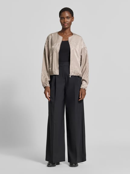 Frauenmodel trägt Blouson aus Viskose-Mix mit Motiv-Stitching Modell 'Ta44mika' von ZABAIONE, beige Töne, Zierperlen, Ganzkörperansicht von vorne.