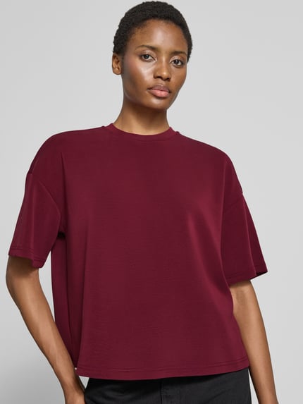 Kobiece model nosi Oversized Sweatshirt aus Modal-Mix model 'TENNY' od Selected w kolorze burgundowym, gładka tekstura, proste kształty, bluza damska, zbliżenie na górną część ciała, widok z przodu