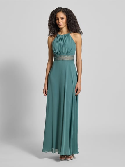 Frauenmodel trägt Abendkleid mit Raffungen von Jake*s Cocktail in Grün, taillierter Schnitt, blickdichtes Unterkleid, Ganzkörperansicht von vorne.
