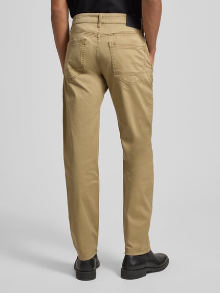 Männermodel trägt Regular Fit Chino aus Baumwoll-Mix von s.Oliver RED LABEL in Beige mit 5-Pocket-Design, Ganzkörperansicht Rückansicht.