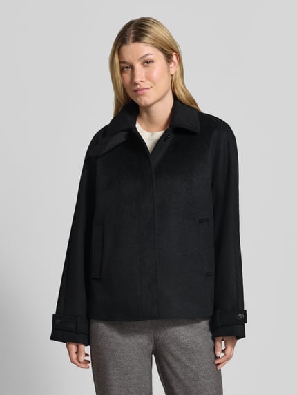 Vrouwenmodel draagt Jacke mit Woll-Anteil van Christian Berg Woman Selection in zwart, steekzakken, platte kraag, rechte pasvorm, mouwsluitingen, knoopsluiting met afdekstrip, materiaalmix, zichtbare textuur, Ganzkörperansicht van voren. Ruglengte maat 36: 63 cm, schouderbreedte: 41 cm, borstwijdte: 58 cm, mouwlengte: 63 cm.