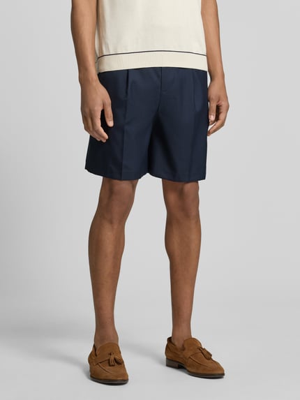Männermodel trägt Loose Fit Bermudas mit Woll-Anteil Modell 'OTTO' von SELECTED HOMME, Optik: Unifarben, Bundfalten, Knopf und verdeckter Reißverschluss, seitliche Eingrifftaschen, Paspeltaschen, dunkle Farbe, glatte Textur, Ganzkörperansicht von vorne.