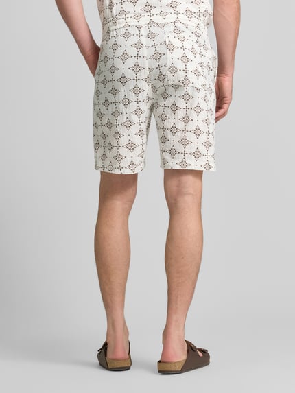Männermodel trägt Relaxed Fit Stoffshorts aus einer Baumwolle von s.Oliver RED LABEL, cremefarben, gemustert, strukturierte Oberfläche, Ganzkörperansicht Rückansicht.