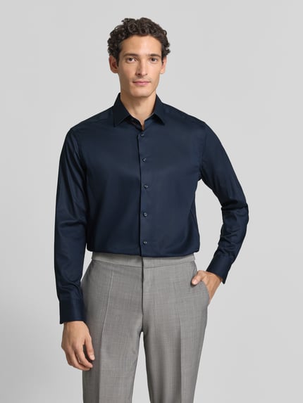 Männermodel trägt Regular Fit Businesshemd mit Kentkragen von OLYMP in Dunkelblau mit feinem Webstruktur-Muster, Ganzkörperansicht von vorne.