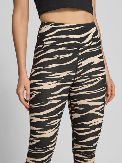 Frauenmodel trägt Slim Fit Leggins aus Viskose-Mix von Lala Berlin mit Allover-Animal-Print, Logo-Detail, Knöchellänge, Nahaufnahme Oberkörper.