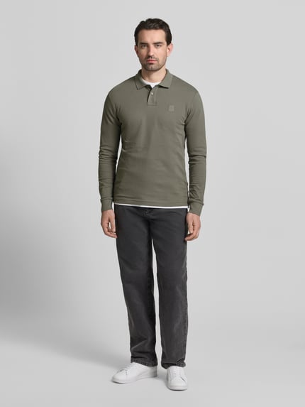 Mannelijk model draagt Slim Fit Poloshirt aus Baumwoll-Mix Modell 'PASSERBY' van BOSS Orange, effen groen, lange mouw, piqué, label stitching op borst, polokraag met twee knopen, volledige lichaamsaanzicht van voren.