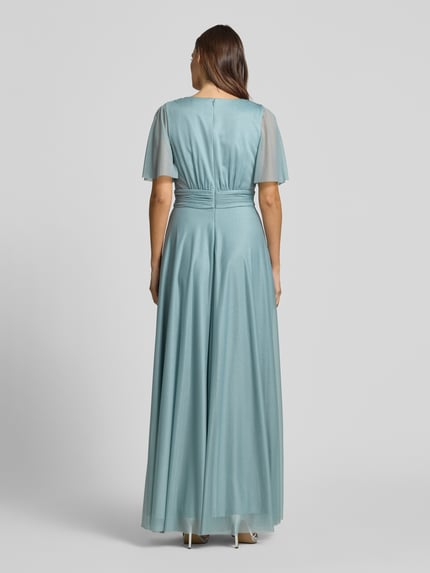 Modelka kobieca nosi Schimmerndes Maxikleid mit V-Ausschnitt und Taillenband von Christian Berg Cocktail, siateczka, linia a, efekt błyszczący, dekolt w serek, tasiemka w talii, długość tyłu w rozmiarze 36: 149 cm, szerokość klatki piersiowej w rozmiarze 36: 35 cm, długość rękawów w rozmiarze 36: 29 cm, jasnoniebieskie, rozkloszowany dół, lekka tekstura, widok całej sylwetki z tyłu.