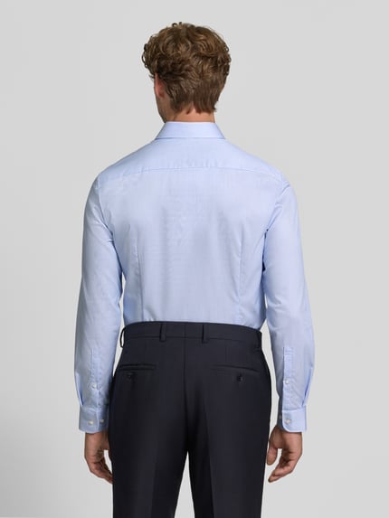 Männermodel trägt Slim Fit Businesshemd aus reiner Baumwolle von Jake*s in Hellblau, glatte Textur, Ganzkörperansicht Rückansicht.