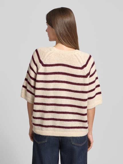 Frauenmodel trägt Strickpullover mit gerippten Abschlüssen von Milano Italy, cremefarben mit weinroten Streifen, lockerer Schnitt, Ganzkörperansicht Rückansicht.