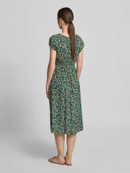 Vrouwenmodel draagt Midikleid aus Viskose mit Smok-Details van Apricot in donkergroen met bloemendessin, getailleerd model, korte mouwen met ruches, ruchedetail aan de hals, ruglengte maat S 105 cm, borstwijdte maat S 40 cm. Volledige lichaamsaanzicht achteraan.