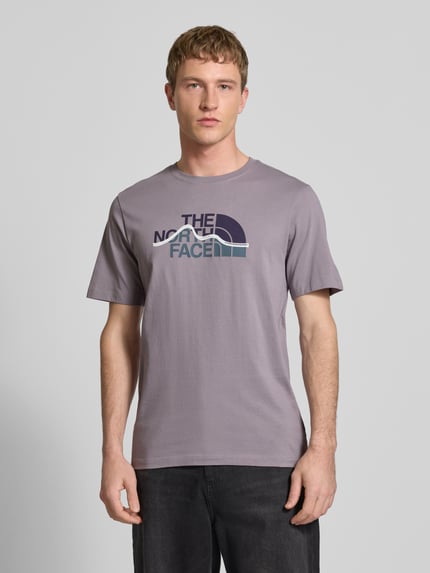 Männermodel trägt Regular fit T-shirt van puur katoen Model 'MOUNTAIN LINE' van The North Face met labelprint, ronde hals, ruglengte maat M 70 cm. Ganzkörperansicht van voren.