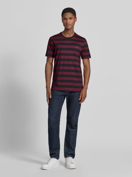 Männermodel trägt Regular Fit T-Shirt mit Logo-Stitching von Christian Berg Men, gestreift in Rot und Dunkelblau, Reine Baumwolle, Rundhalsausschnitt, Rückenlänge bei Größe M 70 cm, Ganzkörperansicht von vorne.