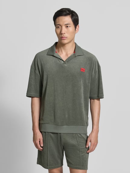 Męski model nosi Regular Fit Poloshirt aus Baumwoll-Mix Modell 'TERRANCE' od HUGO, kolor jednolity, krój relaxed fit, naszywka z logo, kołnierzyk polo, krótki rękaw, materiał sweat, bawełniany mix, ujęcie całej sylwetki z przodu.