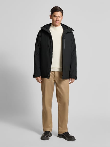 Männermodel trägt schwarzen Parka mit Kapuze und Ärmelriegeln Modell 'BAKERHILL' von Icepeak, Material-Mix, Ganzkörperansicht von vorne.