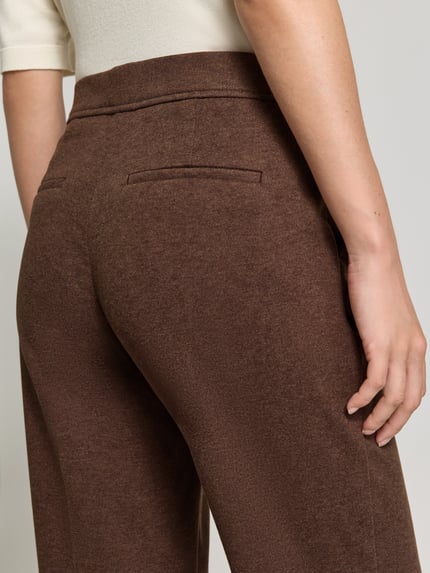Frauenmodel trägt Boocut Fit Stoffhose mit Viskose-Anteil von Christian Berg Woman, braune Farbe, Paspeltaschen, Detailaufnahme Oberschenkel Rückansicht.