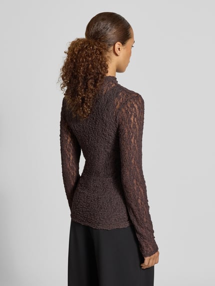 Młodzieżowy model nosi Slim Fit Longsleeve aus Spitze od Rich & Royal, Koronka, krój slim fit, półprzezroczysty materiał, stójka, długość tyłu w rozmiarze S: 68 cm, widok całej sylwetki z tyłu.