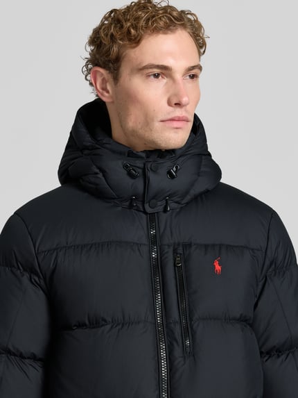 Männermodel trägt schwarze Regular Fit Daunenjacke mit Logo-Stitching von Polo Ralph Lauren, glatte Oberfläche, Nahaufnahme Oberkörper, Herren Daunenjacke von Polo Ralph Lauren