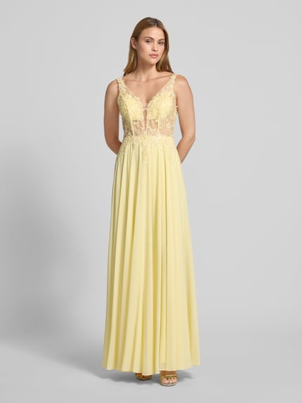 Frauenmodel trägt Abendkleid mit floralem Spitzenbesatz von Mascara, Tailliert, Paillettenbesatz, Semitransparent, V-Ausschnitt, Ganzkörperansicht von vorne.