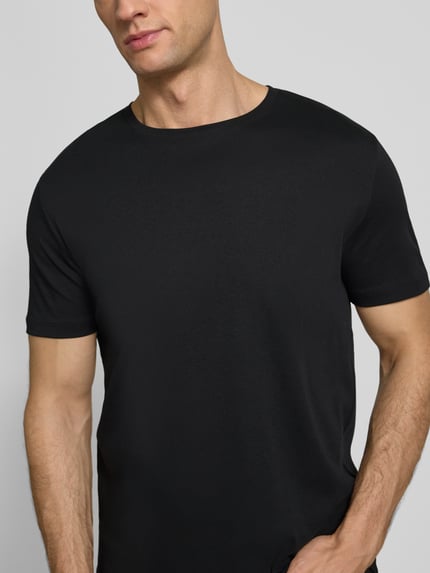 Männermodel trägt T-Shirt mit geripptem Rundhalsausschnitt von Christian Berg Men, schwarze Baumwolle, Regular Fit, Nahaufnahme Oberkörper.