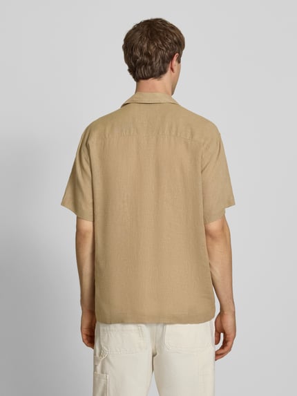 Männermodel trägt Relaxed Fit Freizeithemd aus Leinen-Viskose-Mix Modell 'LAURENCE' von Only & Sons, Optik: Unifarben, Passform: Relaxed-Fit, Hemdkragen: Reverskragen, Knopfleiste: Einreihig, Ärmelform: Kurzarm, Brusttasche, beiges Material, Ganzkörperansicht Rückansicht.