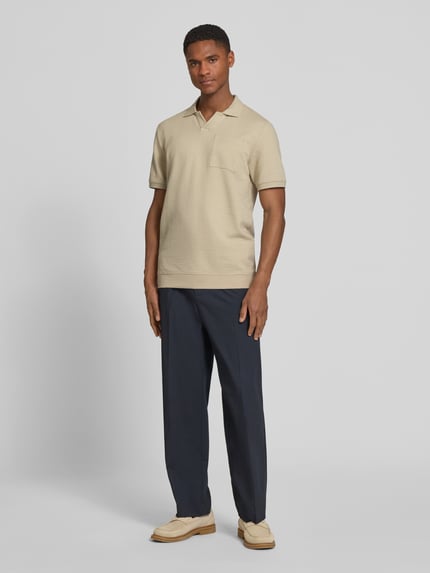 Männermodel trägt Regular Fit Poloshirt aus Baumwoll-Mix von s.Oliver RED LABEL in Beige, kurzarm, Polokragen, strukturierte Seersucker-Optik, unifarben, Ganzkörperansicht von vorne
