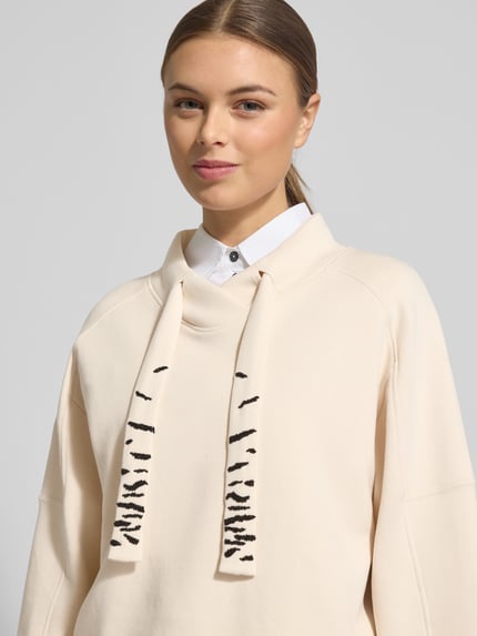Kobiece modelka nosi Oversized Sweatshirt mit Tunnelzug von Marc Cain, mieszanka bawełny z dodatkiem streczu, stójka, tunel. Zbliżenie na górną część ciała.