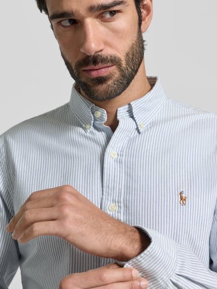 Männermodel trägt Slim Fit Freizeithemd aus reiner Baumwolle Modell 'OXFORD' von Polo Ralph Lauren, gestreift, Label-Stitching, Nahaufnahme Oberkörper.
