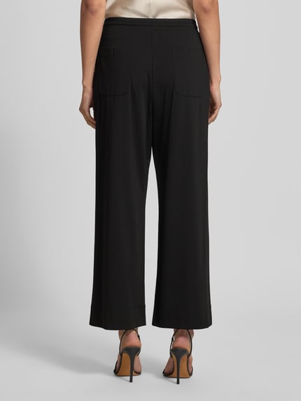 Kobiece modelka nosi Regular Fit Anzughose mit elastischem Bund Modell 'MODICO' od Weekend Max Mara, czarny, wysoki stan, gładka faktura, boczne kieszenie, widok całej sylwetki z tyłu.