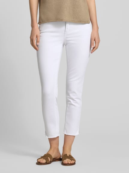 Vrouwenmodel draagt Slim Fit Jeans met franjes aan de zoom model 'PIPER SHORT' van Cambio in wit, katoenmix met stretch, nauwsluitende pasvorm, steekzakken en achterzakken, knoop- en ritssluiting, detailopname vooraan.